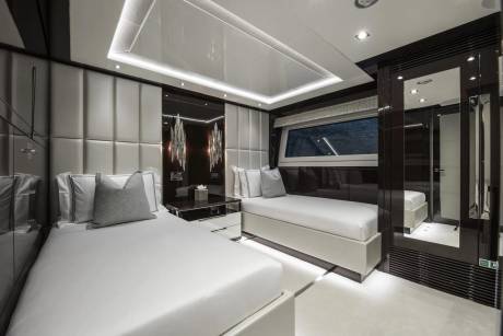 Luxurious twin beds with plush headboards and elegant lighting create a serene retreat on this modern yacht.