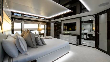 Luxurious yacht bedroom features a king-size bed, modern entertainment center, and an en-suite bathroom with marble accents.