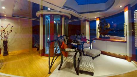 Elegant seating and a striking ship model adorn this luxurious yacht lounge with panoramic views.