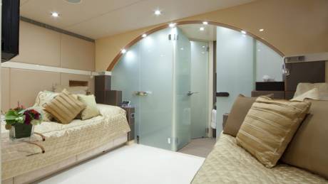 Luxurious yacht cabin features a plush bed and a frosted glass en-suite bathroom.