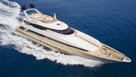 A luxurious yacht glides through the deep blue ocean, leaving a trail of white foam in its wake.