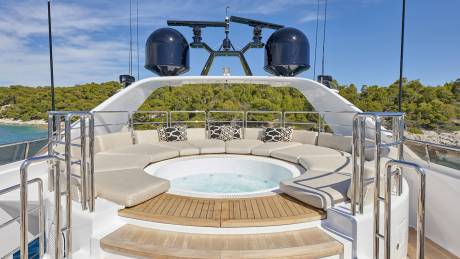 Relax in the circular jacuzzi surrounded by plush seating and a scenic island backdrop.