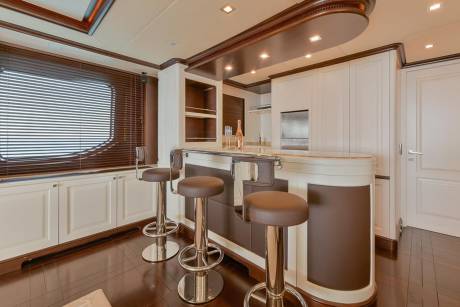 Luxurious bar stools and a sleek counter invite guests to enjoy drinks in this elegant yacht interior.
