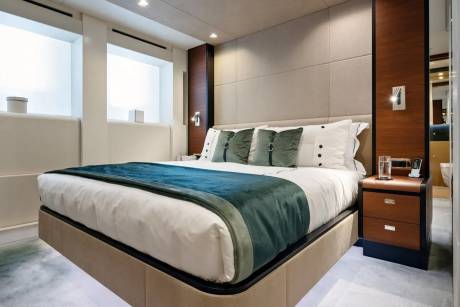 Luxurious yacht stateroom features a plush bed, elegant wood accents, and a serene ambiance for ultimate relaxation.