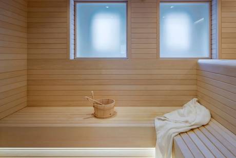 A serene wooden sauna features frosted windows and a towel draped over a bench, creating a tranquil atmosphere.