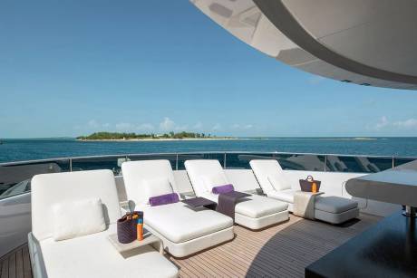 Relax on plush loungers on the deck of a luxury yacht overlooking a serene tropical island.