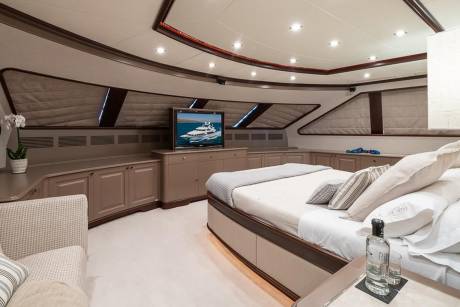 Luxurious yacht accommodations feature a plush bed, entertainment center, and elegant cabinetry for ultimate comfort at sea.