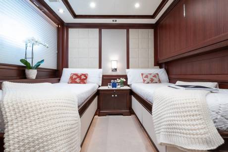Luxurious twin beds with plush throws and decorative pillows await in this elegant stateroom.