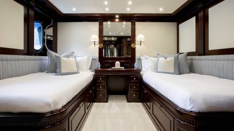 Luxurious twin beds flank a dark wood desk and mirror, offering a serene retreat with a view of icy landscapes.
