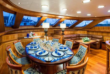 A beautifully set dining table awaits guests aboard a luxurious yacht, bathed in the warm glow of interior lights.