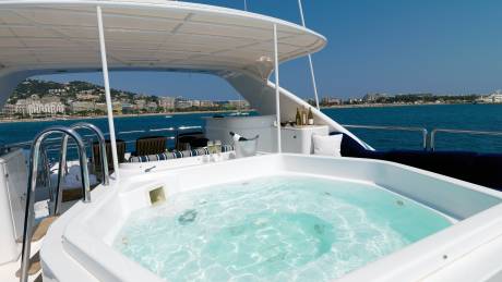 Relax in the bubbling turquoise waters of this yacht's jacuzzi with a stunning coastal view.