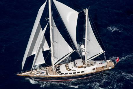 A majestic sailing yacht glides through the deep blue ocean, its white sails billowing in the wind.