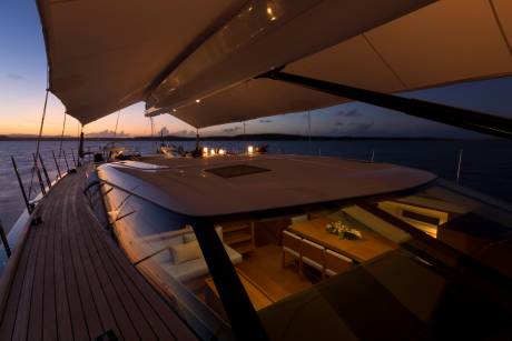 A luxurious yacht's deck is illuminated by ambient lights at twilight, revealing a beautifully set dining table within.