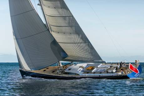 The majestic Farfalla yacht glides through the azure waters under a clear sky, its sails billowing in the wind.