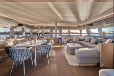 Luxurious yacht interiors offer panoramic views of a serene waterfront landscape bathed in warm sunlight.