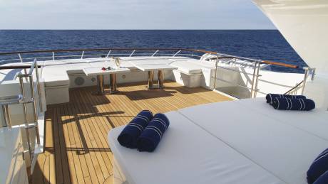 A romantic setting awaits on the deck of this luxurious yacht with champagne and a rose by the tranquil blue sea.
