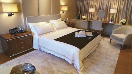 Luxurious robes await on a neatly made bed in this opulent stateroom.