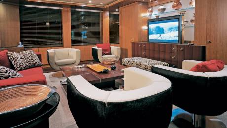 Luxurious yacht interiors feature plush seating, a large television, and elegant wooden cabinetry.