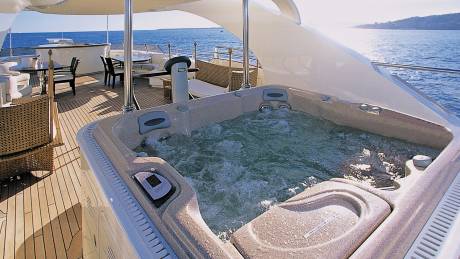 Relax in the bubbling hot tub on the deck of this luxurious yacht, surrounded by the sparkling blue sea.
