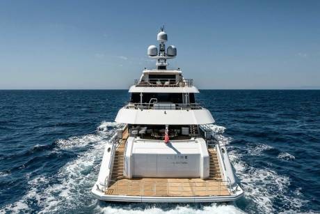 A luxurious white yacht glides through the deep blue ocean under a clear sky.