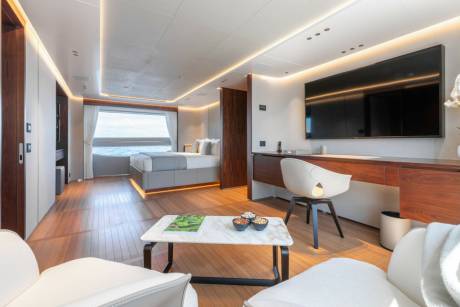 Luxurious yacht cabin offers a serene retreat with a comfortable bed, modern desk, and stunning ocean views.