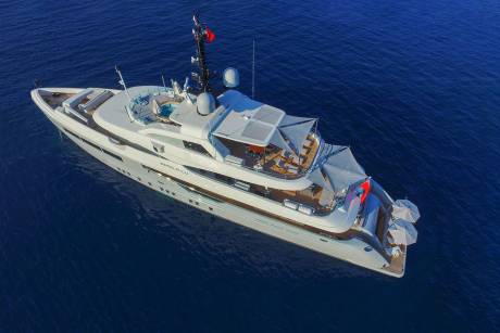 A luxurious white yacht glides serenely through the deep blue ocean under a clear sky.