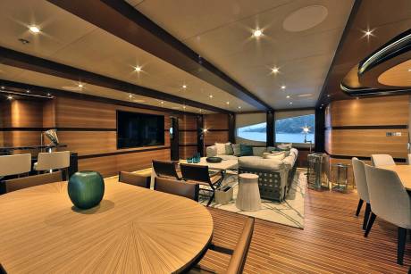 Luxurious yacht interiors feature a spacious lounge with a large television, comfortable seating, and a dining area overlooking the water.