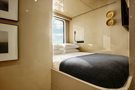 A cozy cabin features a plush bed, a window with a sky view, and minimalist decor.