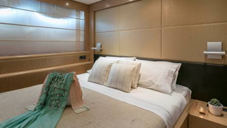 A serene bedroom features a neatly made bed adorned with plush pillows and a delicate embroidered garment draped over the duvet.