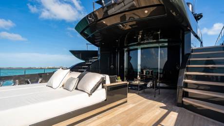 Luxurious outdoor seating on a sleek black yacht offers a perfect spot to enjoy the ocean breeze and sunny skies.