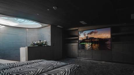A luxurious yacht is displayed on a large screen in a dimly lit room with zebra-print seating.
