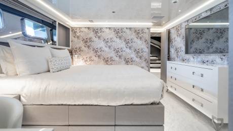 Luxurious yacht bedroom features a plush bed, leopard-print wallpaper, and a sleek dresser with mirrored accents.