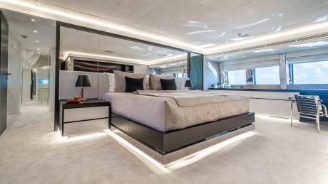 Luxurious yacht bedroom features a king-sized bed with quilted bedding and ambient under-bed lighting.
