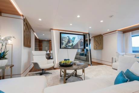 Luxurious white sofas and a sleek entertainment system create a modern living space on this opulent yacht.