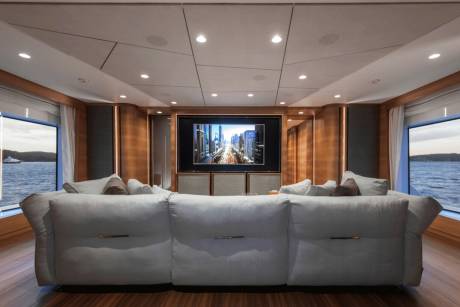 Luxurious yacht interiors offer stunning panoramic views of the water from a plush seating area facing a large entertainment screen.
