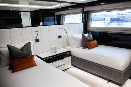 Luxurious twin beds with plush pillows and a view of the water await in this elegant yacht cabin.