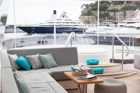Relax on the luxurious deck of a yacht, complete with plush seating and a soothing hot tub, overlooking a picturesque harbor.