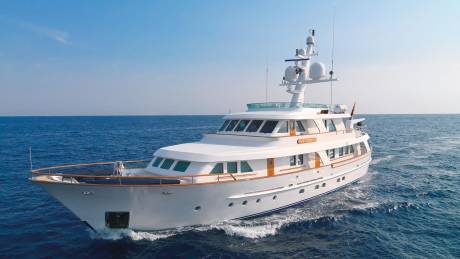 A luxurious white yacht cruises through the deep blue ocean under a clear sky.