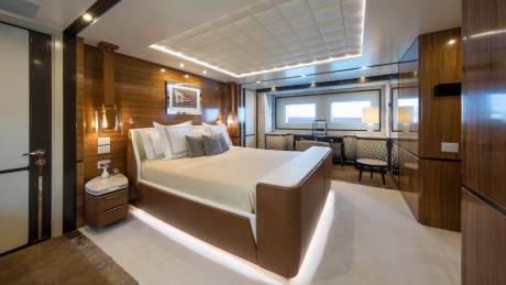 Luxurious yacht master suite features a plush bed, rich wood paneling, and ambient lighting for ultimate relaxation.