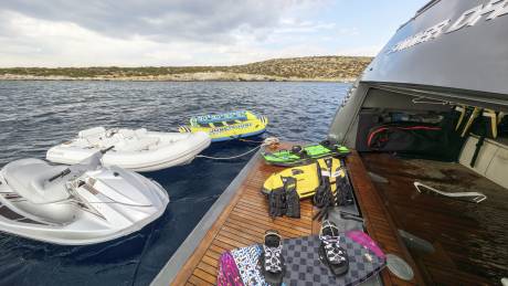 Ready for aquatic adventures, a collection of jet skis, inflatable tubes, and wakeboards are neatly arranged on a yacht's deck.