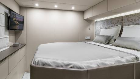 Luxurious bedding and a mounted television create a serene and modern retreat aboard this elegant yacht.