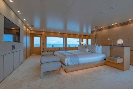 Luxurious yacht master suite offers serene ocean views from a spacious, elegantly appointed bedroom.