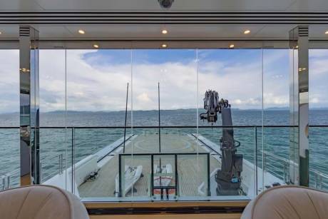 Luxurious yacht interiors offer stunning ocean views through floor-to-ceiling windows, showcasing a helideck and crane.
