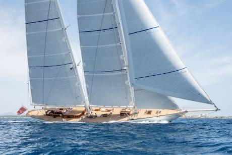 A majestic sailing yacht glides through the azure waters under a vast expanse of billowing sails.