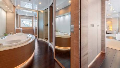 A luxurious yacht bathroom features a curved soaking tub and a sleek, modern shower with mirrored walls.