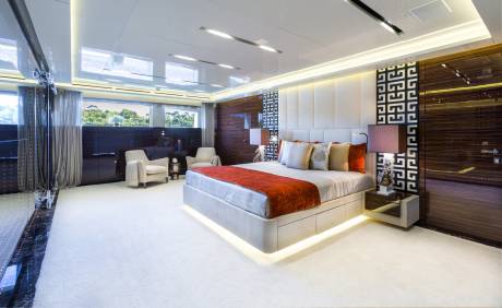 Luxurious yacht bedroom features a plush bed, elegant seating, and stunning ocean views.