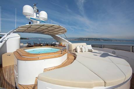 Relax in the luxurious jacuzzi or lounge on the expansive sun deck of this opulent yacht overlooking a picturesque coastline.