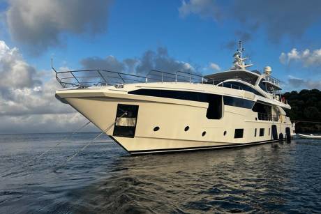 A luxurious white yacht floats serenely on calm blue waters under a dramatic sky.