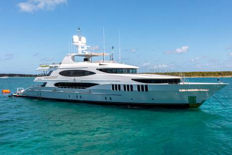 A luxurious white yacht floats serenely on crystal-clear turquoise waters under a bright blue sky.