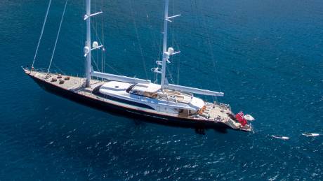 A majestic sailing yacht glides through the deep blue ocean, its tall masts reaching for the sky.